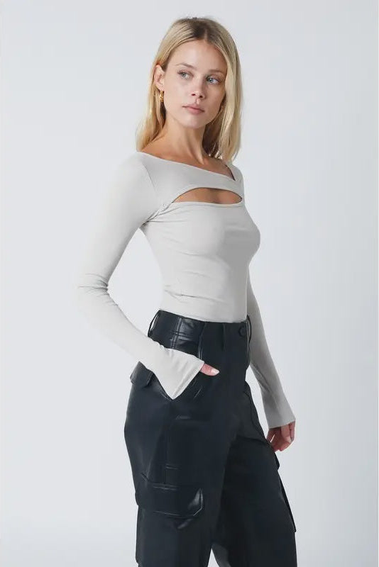 Woman wearing a light gray off-shoulder top and black pants on a white background