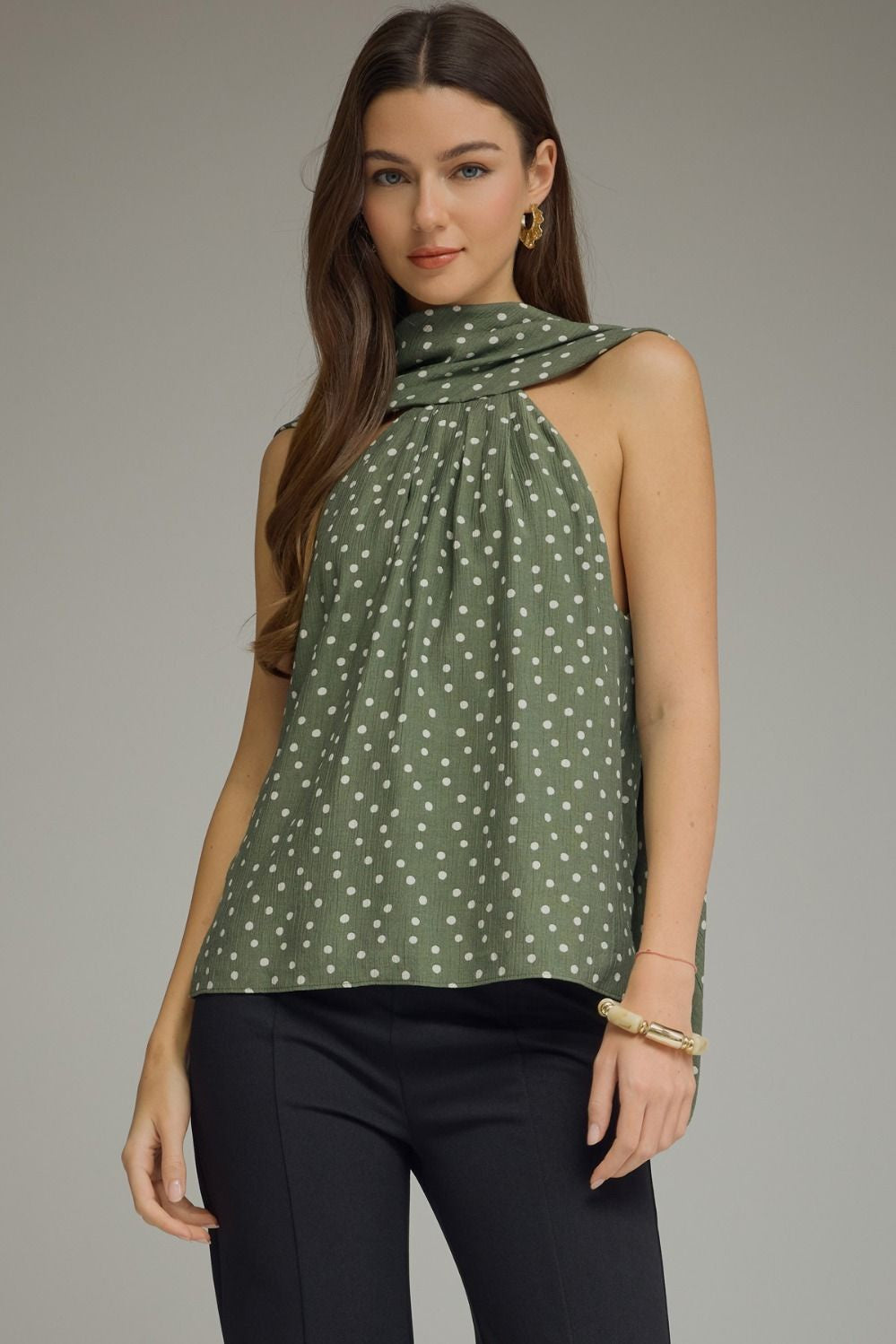 Woman wearing a green polka dot top against a gray background