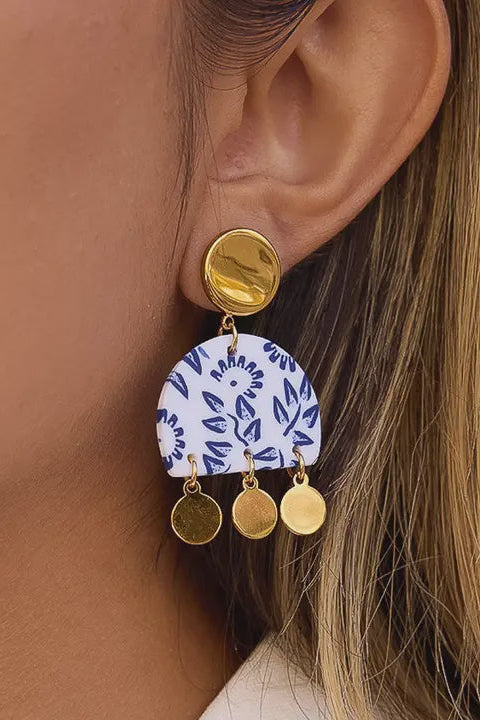 Earring with blue and white pattern and gold accents worn by a person