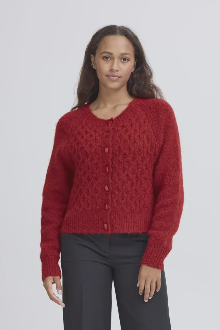 Woman wearing a red knitted cardigan against a plain background