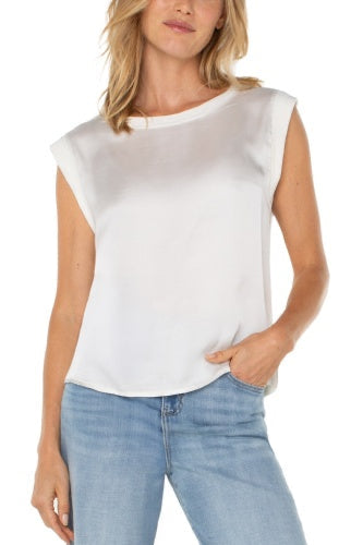 Woman wearing a white sleeveless top and light blue jeans on a white background