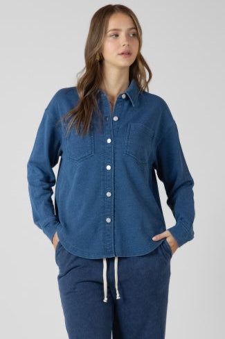 Woman wearing a blue denim shirt and pants on a plain background