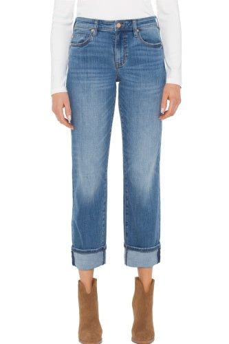 Person wearing blue jeans and brown boots on a white background