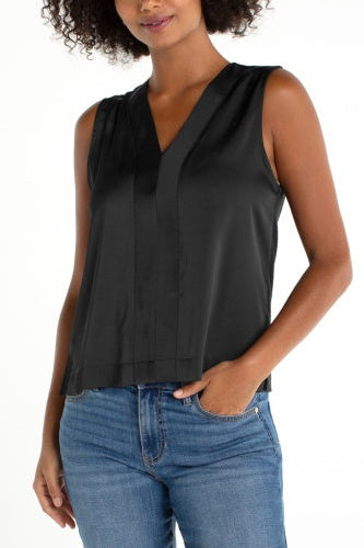 Woman wearing a black sleeveless top and blue jeans on a white background