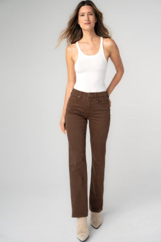 Woman wearing a white tank top and brown pants on a gray background