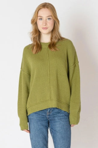 Woman wearing a green sweater and blue jeans on a white background