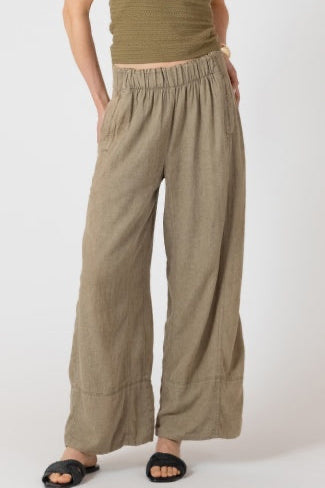 Person wearing a green top and beige wide-leg pants on a white background