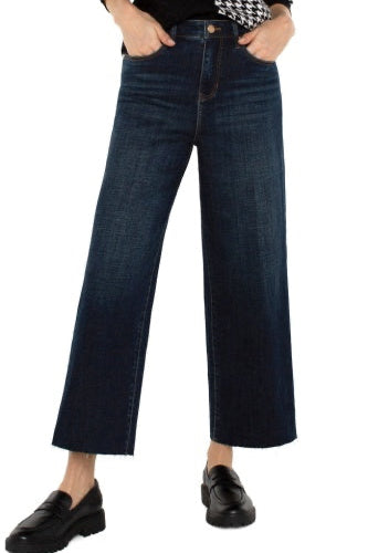 Person wearing dark blue wide-leg jeans on a white background