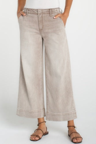 Person wearing beige wide-leg jeans on a white background