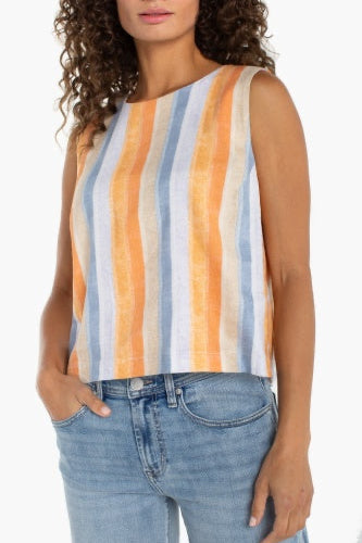 Woman wearing a sleeveless striped top with orange, blue, and white stripes and blue jeans.