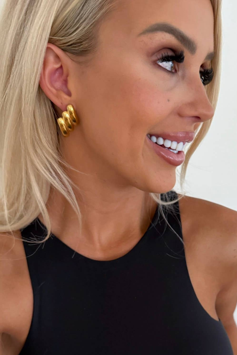 Woman wearing gold hoop earrings with a neutral background