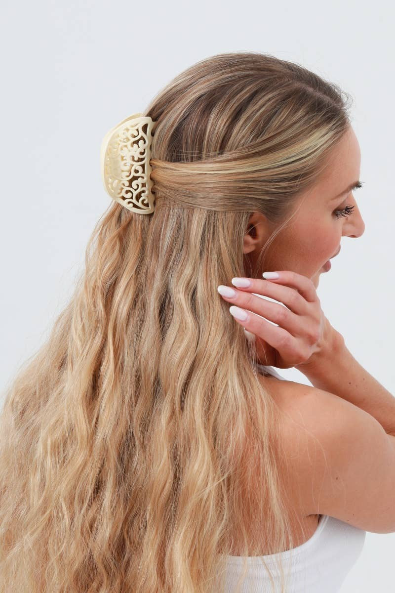 Woman with long blonde hair wearing a gold headband against a white background