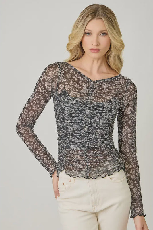 Woman wearing a floral lace long-sleeve top against a plain background