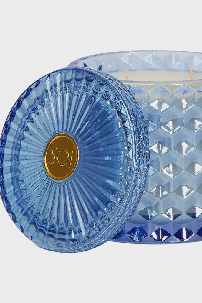 Blue textured glass candle with a gold 'Soy' label on a light gray background