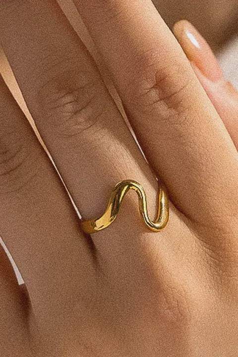 Gold ring on a person's finger with a neutral background