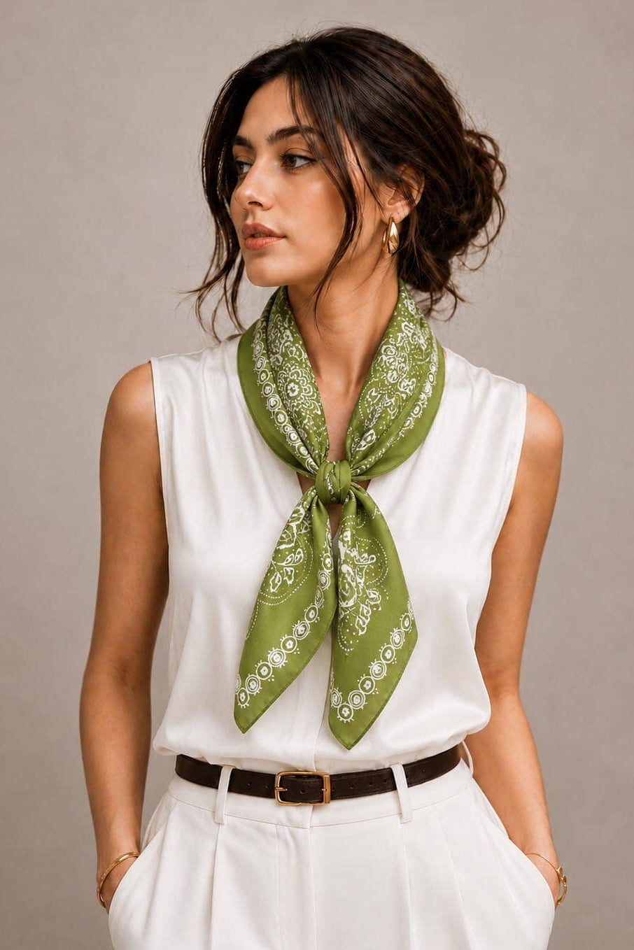 Woman wearing a green scarf with white patterns on a plain background