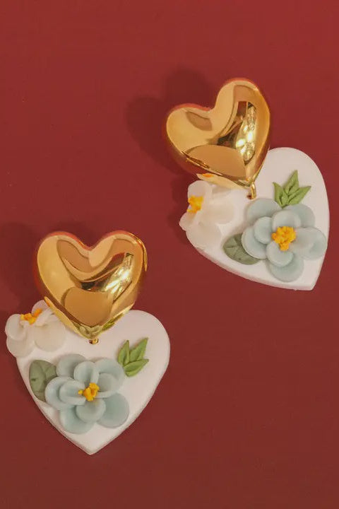 Heart-shaped earrings with gold centers and floral designs on a red background