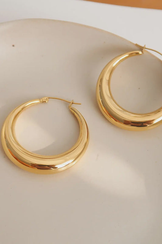 Gold hoop earrings on a beige surface