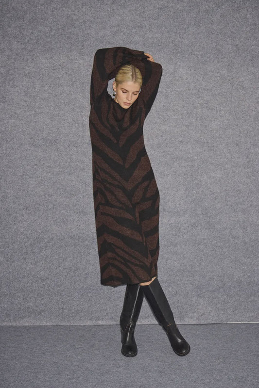 Person wearing a brown and black zebra-striped dress against a gray background