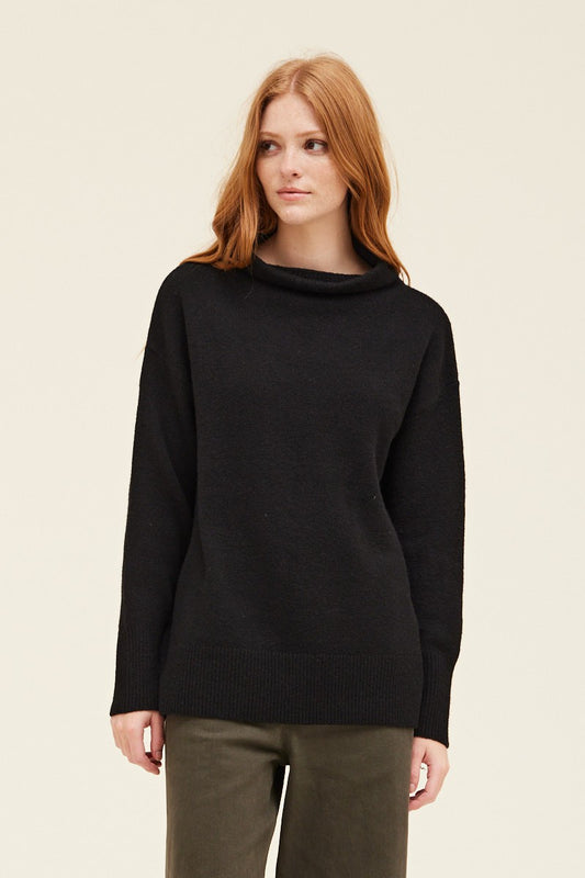 Woman wearing a black sweater against a beige background