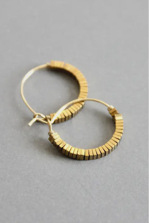 Gold hoop earrings on a gray background