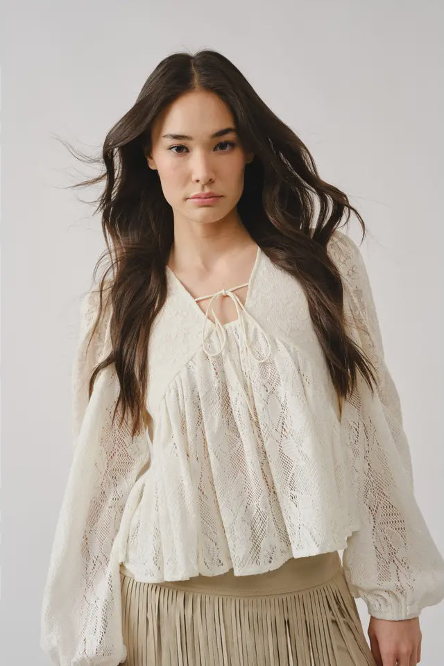 Woman wearing a white lace blouse against a plain background