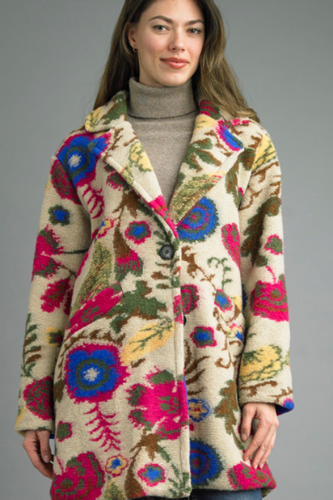 Woman wearing a colorful patterned coat against a gray background