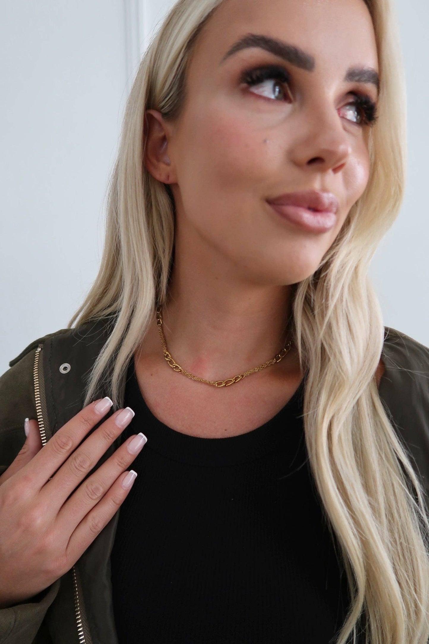 Woman wearing a gold necklace against a white background