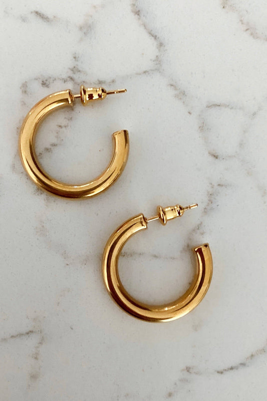 Gold hoop earrings on a marble surface