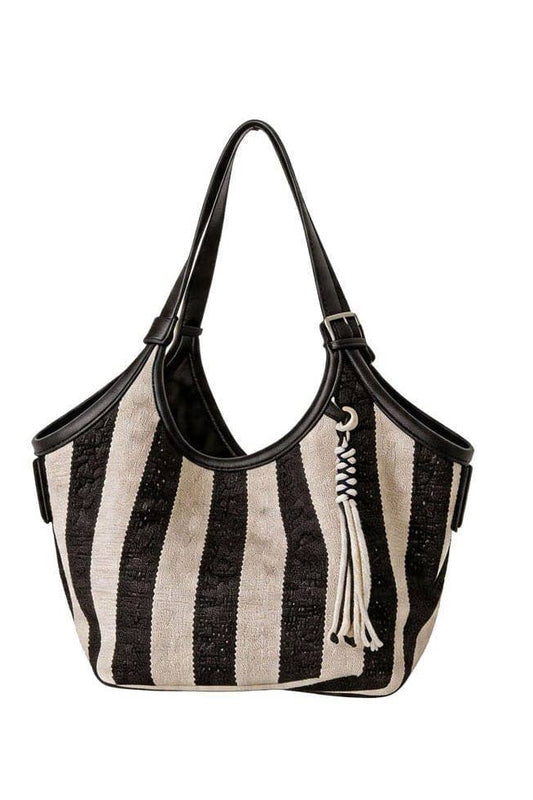 A black and cream striped woven shoulder bag with black leather trim, double shoulder straps, and a decorative white tassel charm, shown against a plain white background.