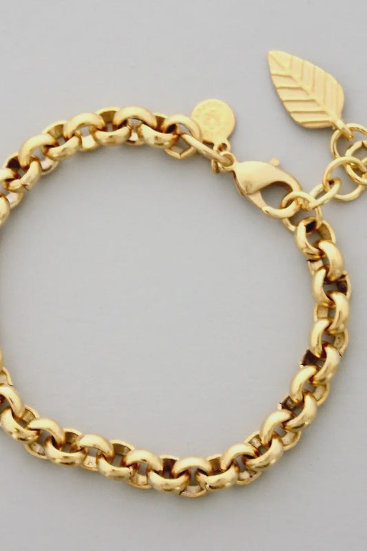 Gold chain bracelet with leaf charm on a gray background