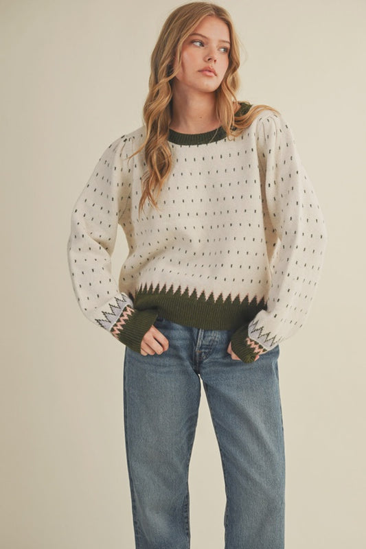 Woman wearing a patterned sweater and jeans on a plain background