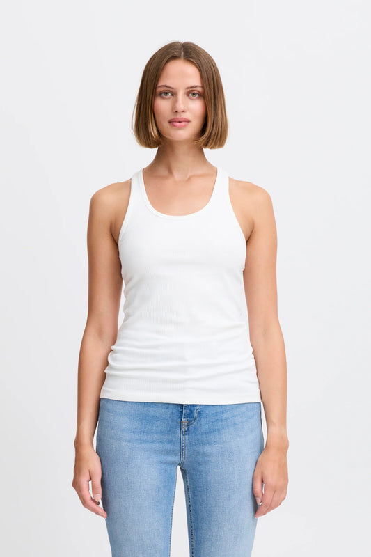 Woman wearing a white tank top and blue jeans on a plain background