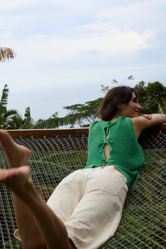 Person sitting in a hammock with a scenic background of trees and sky.