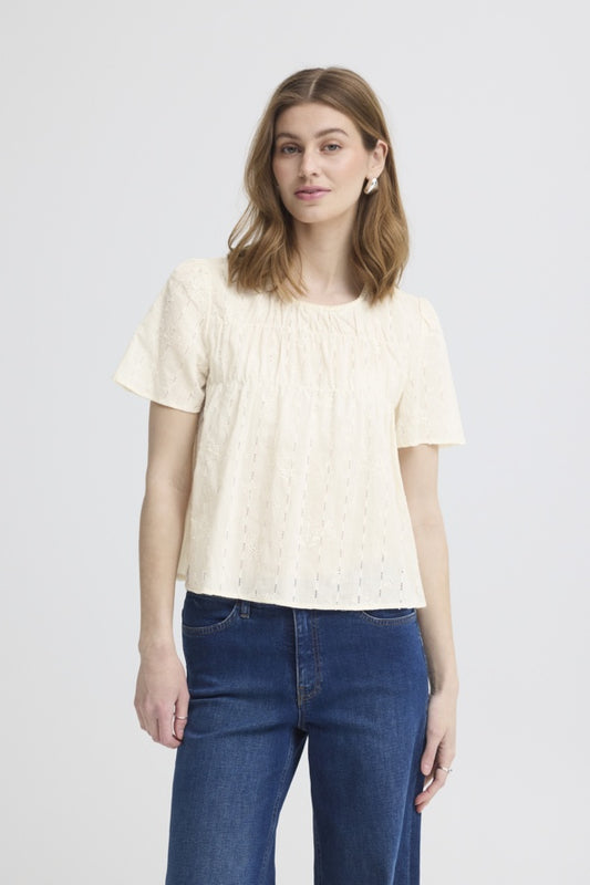 Woman wearing a light-colored t-shirt and blue jeans on a plain background