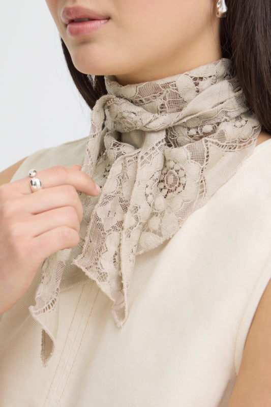 Woman wearing a beige lace scarf with a plain background