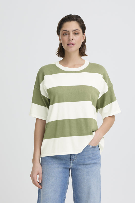 Woman wearing a green and white striped sweater with blue jeans on a light gray background