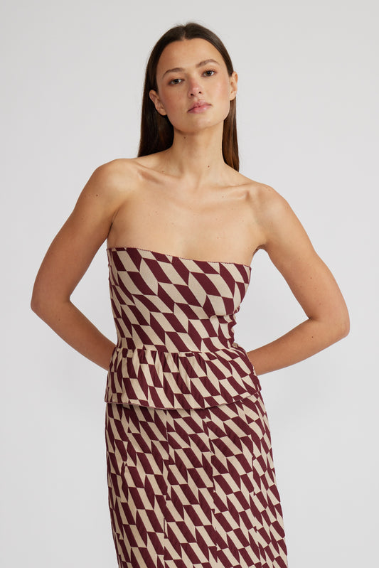 Woman wearing a strapless dress with a geometric pattern on a plain background