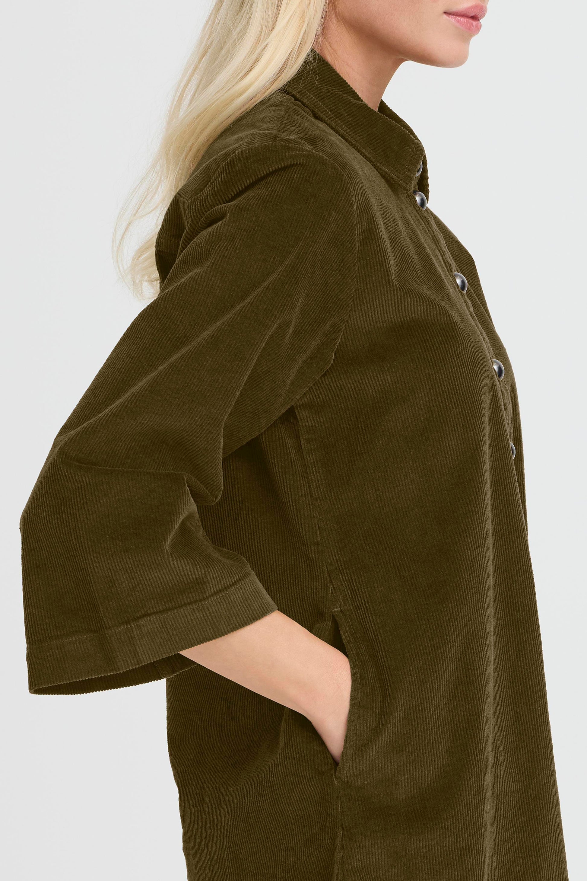 Person wearing a brown corduroy shirt with a plain background