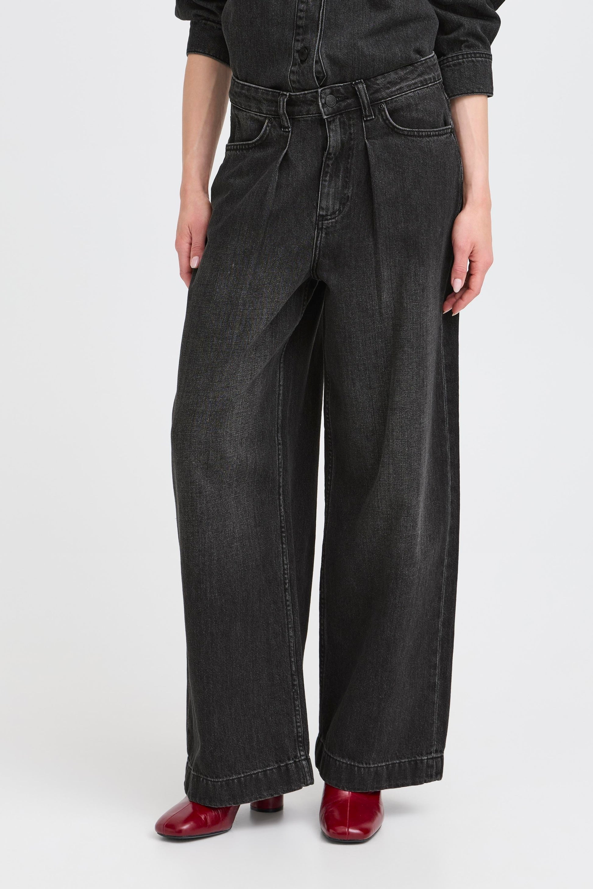 Person wearing black wide-leg jeans on a white background