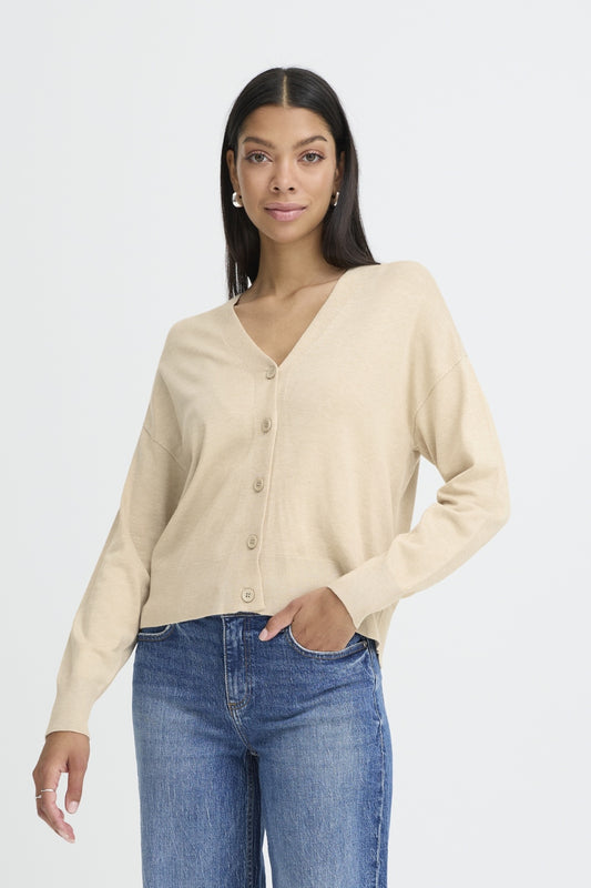 Woman wearing a beige cardigan and blue jeans on a white background
