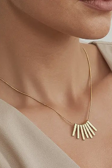Gold necklace with a unique pendant worn by a person against a neutral background
