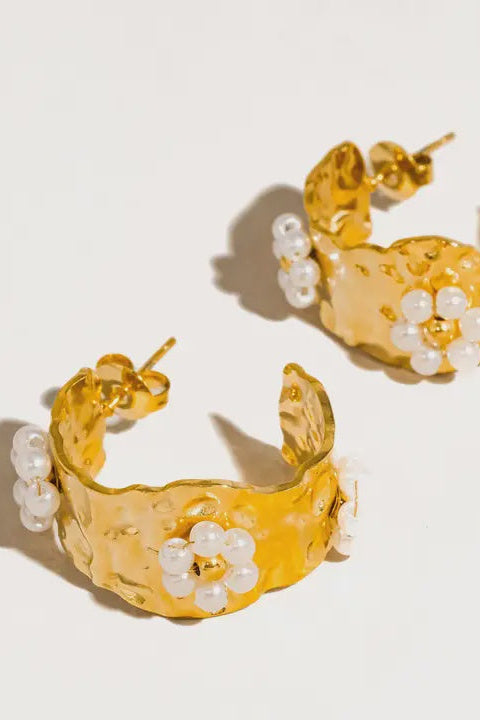 Gold hoop earrings with pearl accents on a light background