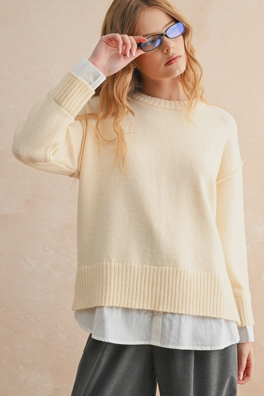 Woman wearing a beige sweater over a white shirt with sunglasses on a beige background