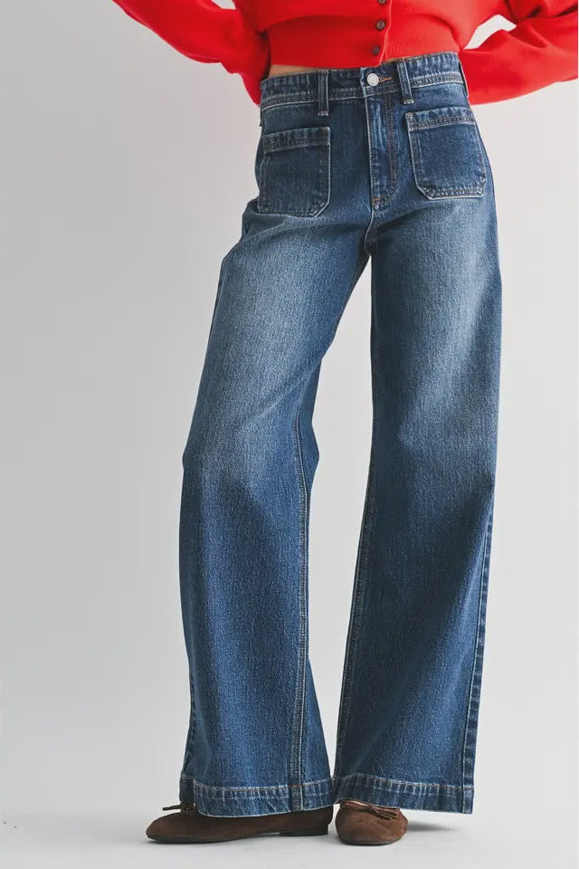 Blue jeans worn with a red top on a white background