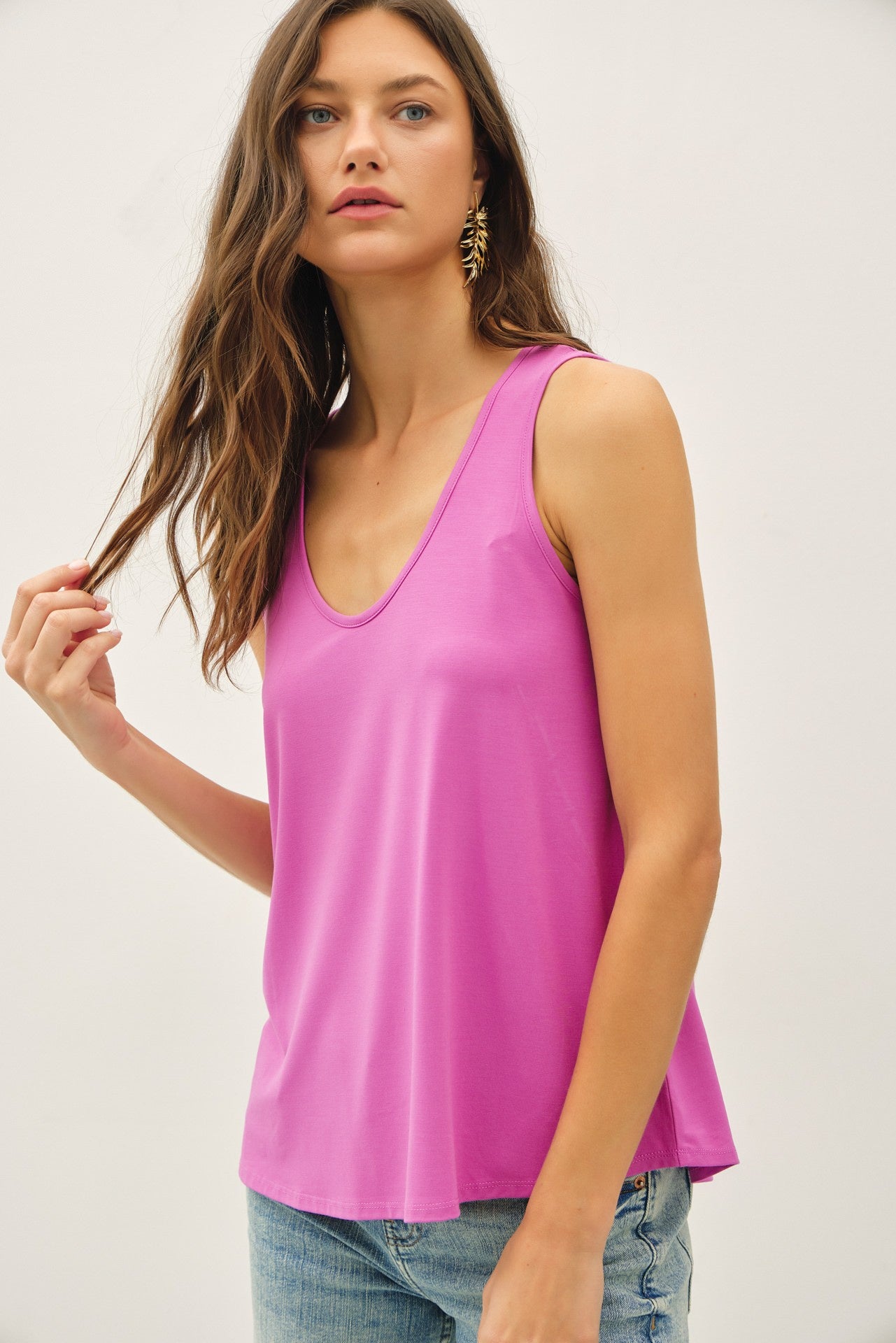 Woman wearing a bright pink sleeveless top against a plain background