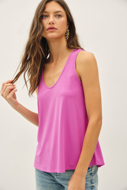 Woman wearing a bright pink sleeveless top against a plain background