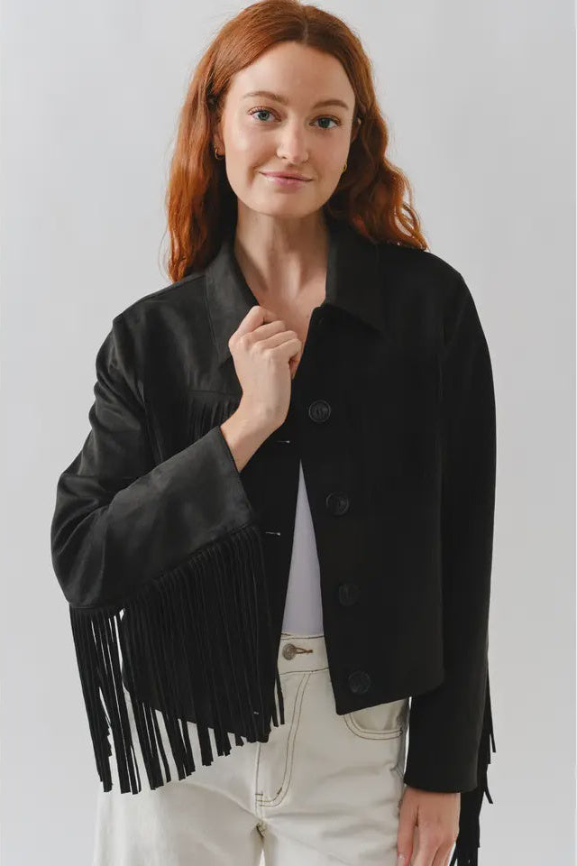 Woman wearing a black fringed jacket on a plain background