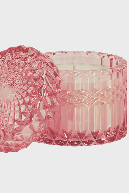 Pink glass candle holder with intricate designs on a white background