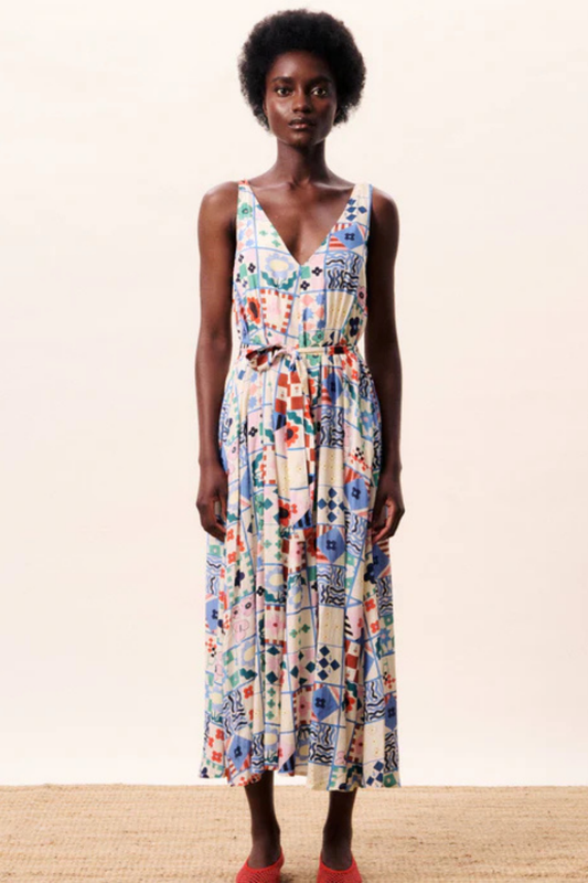 Woman wearing a colorful floral dress on a plain background